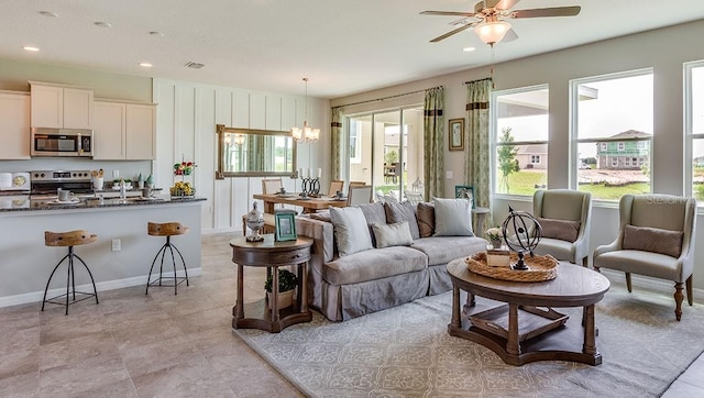 living room with ceiling fan with notable chandelier and a healthy amount of sunlight