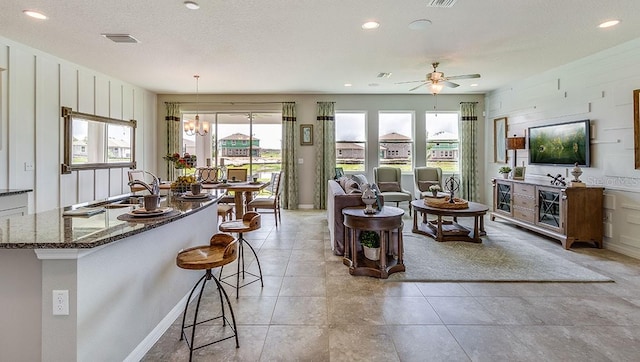 tiled living room with sink, ceiling fan with notable chandelier, and a textured ceiling