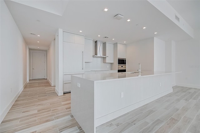 kitchen with an island with sink, modern cabinets, white cabinets, and light countertops