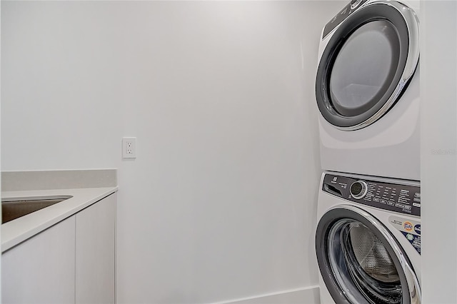 laundry area featuring a sink, cabinet space, and stacked washer / drying machine