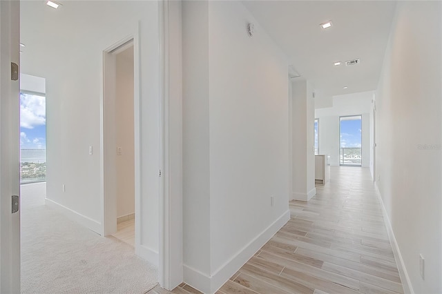 hall featuring light wood finished floors, visible vents, and baseboards