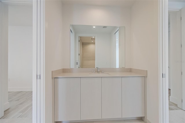 bathroom with baseboards, wood finished floors, and vanity