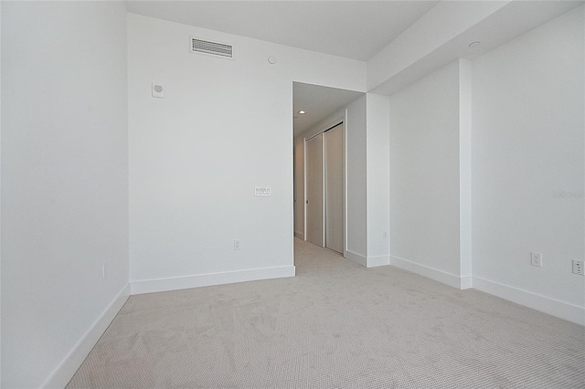 spare room featuring visible vents, light carpet, and baseboards