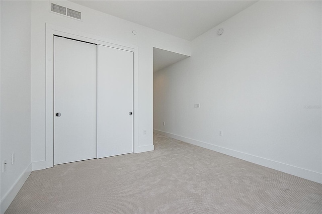 unfurnished bedroom with light colored carpet, a closet, visible vents, and baseboards