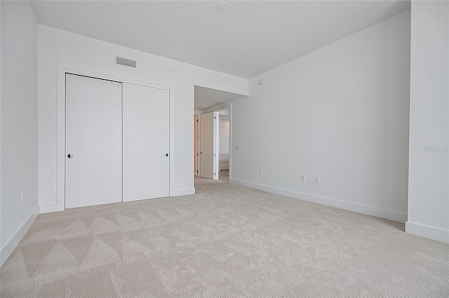 unfurnished bedroom featuring light carpet, a closet, visible vents, and baseboards