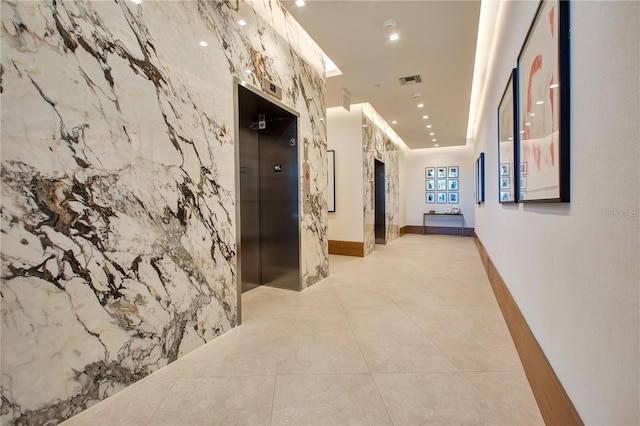 hallway with elevator, light tile patterned floors, and visible vents