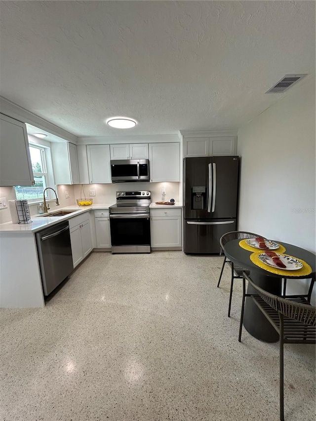 kitchen featuring visible vents, white cabinetry, a sink, light countertops, and stainless steel appliances