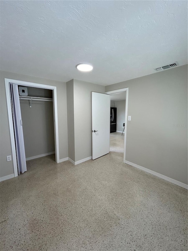 unfurnished bedroom with visible vents, baseboards, light speckled floor, and a textured ceiling