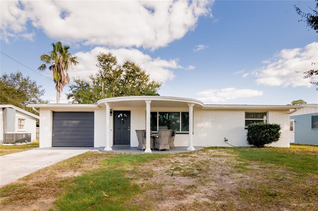 single story home featuring brick siding, a garage, concrete driveway, a front yard, and a porch