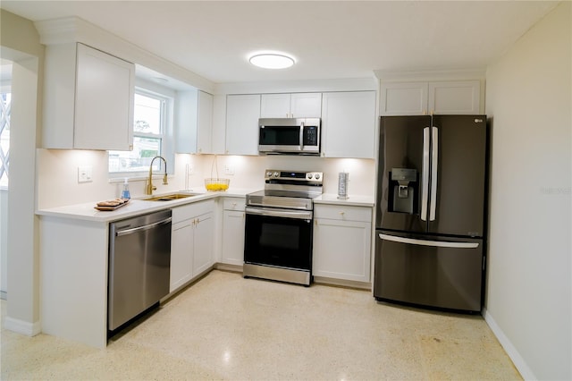 kitchen with stainless steel appliances, white cabinetry, light countertops, and a sink