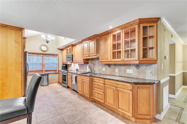 kitchen featuring appliances with stainless steel finishes, backsplash, lofted ceiling, dark stone counters, and sink