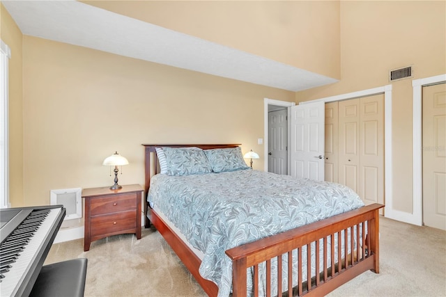 bedroom featuring light colored carpet and multiple closets