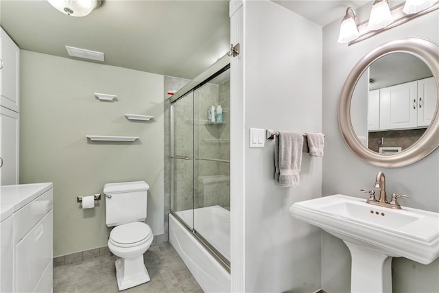 full bathroom featuring tile patterned flooring, shower / bath combination with glass door, sink, washing machine and clothes dryer, and toilet