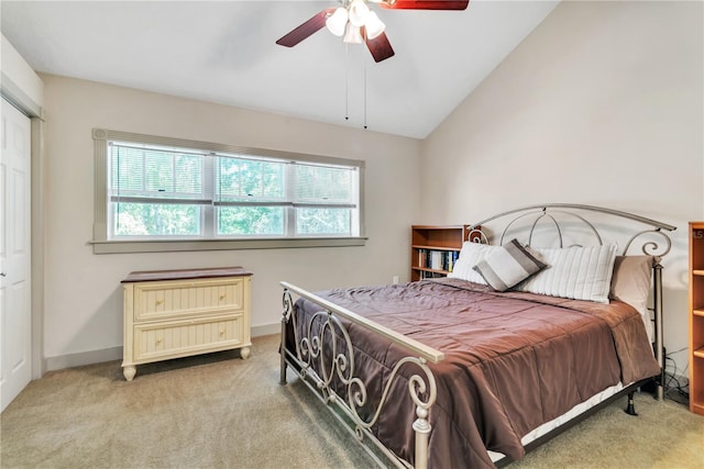 carpeted bedroom with ceiling fan, a closet, and vaulted ceiling