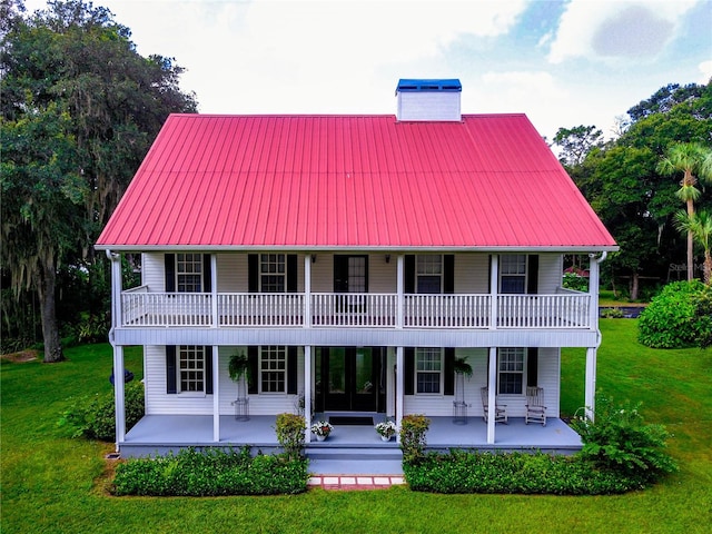 view of front of house featuring a balcony, a front yard, and a patio