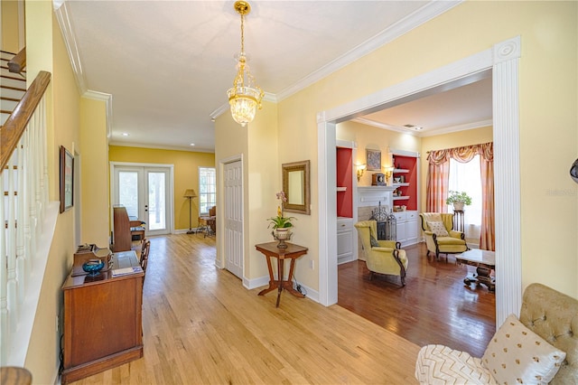 interior space featuring light wood-type flooring, an inviting chandelier, plenty of natural light, and ornamental molding