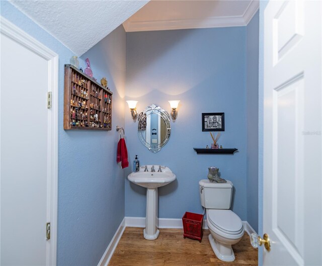 bathroom with toilet, crown molding, and hardwood / wood-style flooring