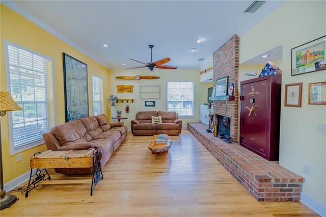 living room featuring hardwood / wood-style floors, ornamental molding, brick wall, a fireplace, and ceiling fan