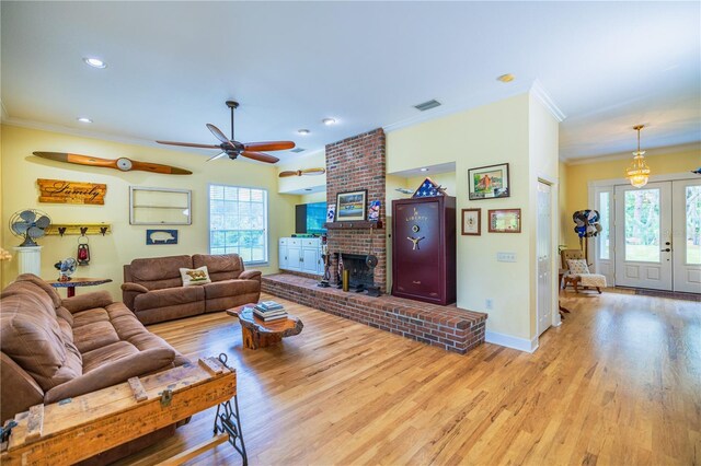 living room featuring light hardwood / wood-style floors, a wealth of natural light, ceiling fan, and a brick fireplace