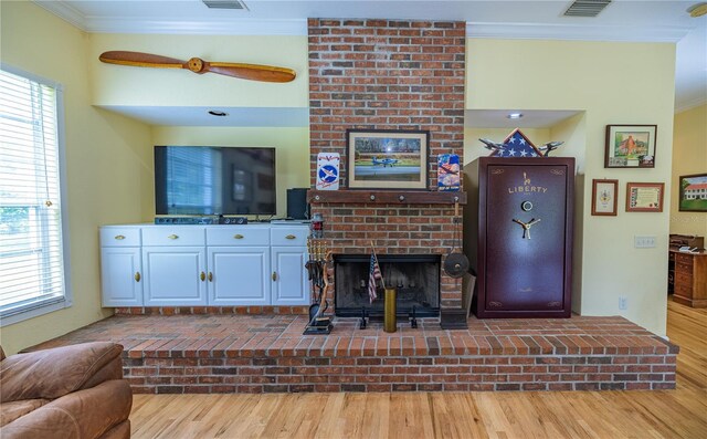 living room with ornamental molding, a fireplace, light hardwood / wood-style flooring, ceiling fan, and brick wall