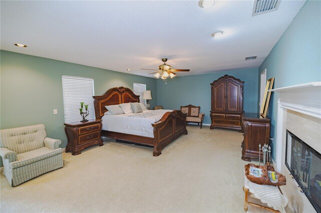 carpeted bedroom featuring ceiling fan and a fireplace