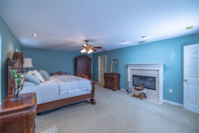 bedroom featuring ceiling fan, a high end fireplace, and light colored carpet