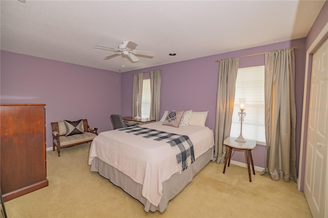 bedroom with ceiling fan, light colored carpet, and a closet