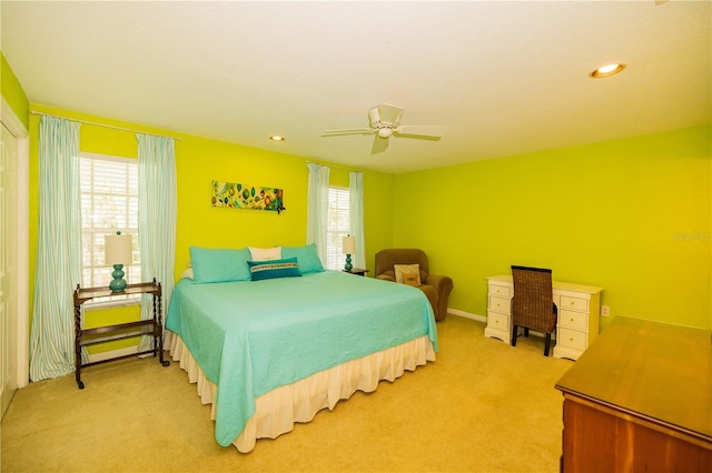 bedroom featuring multiple windows, ceiling fan, and light colored carpet