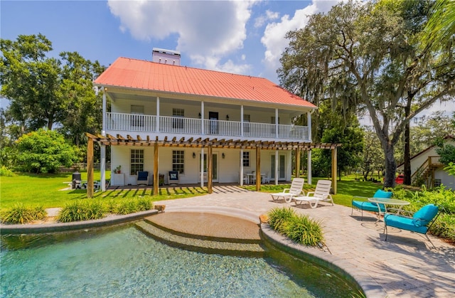 rear view of property featuring a balcony, a pergola, a patio area, and a yard