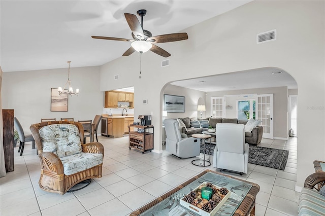 living room with ceiling fan with notable chandelier, high vaulted ceiling, sink, and light tile patterned floors