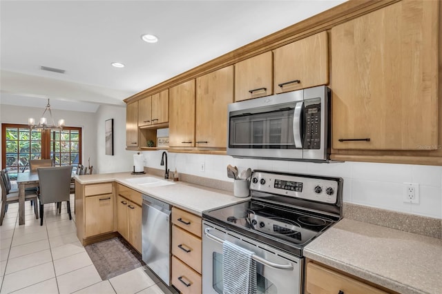 kitchen with sink, light tile patterned floors, appliances with stainless steel finishes, light brown cabinetry, and decorative light fixtures