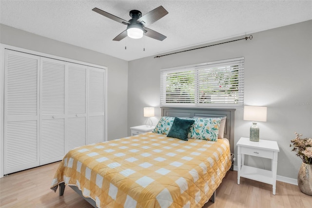 bedroom with ceiling fan, a closet, light hardwood / wood-style floors, and a textured ceiling