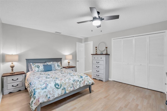 bedroom featuring ceiling fan, a closet, a textured ceiling, and light wood-type flooring