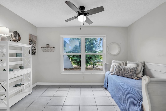 tiled bedroom with ceiling fan and a textured ceiling