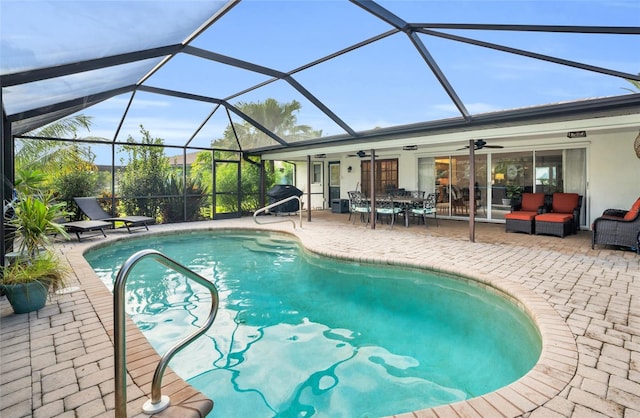 view of pool featuring outdoor lounge area, a patio, ceiling fan, and glass enclosure