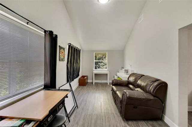 living area with visible vents, baseboards, vaulted ceiling, and wood finished floors