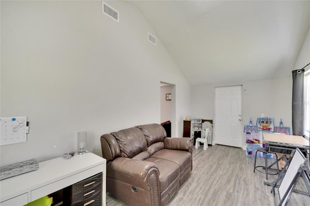 living area with vaulted ceiling, visible vents, and light wood-style floors