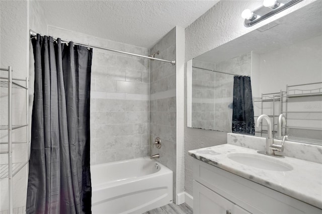 bathroom with a textured wall, shower / bath combo with shower curtain, vanity, and a textured ceiling