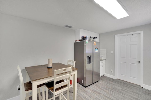 dining space featuring light wood-type flooring, baseboards, and visible vents