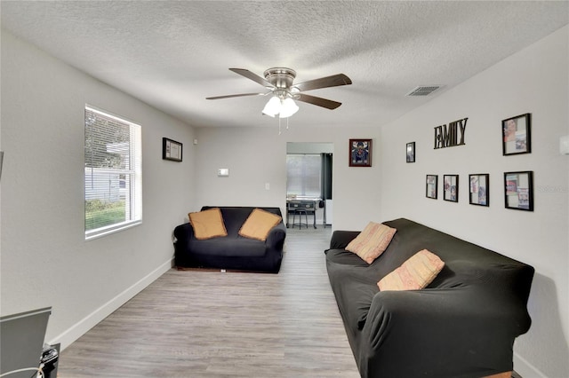 living room featuring ceiling fan, a textured ceiling, and wood-type flooring