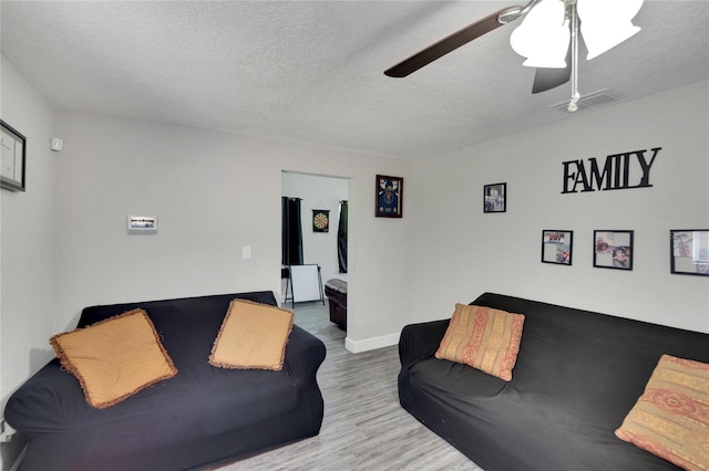 living room featuring a textured ceiling, wood-type flooring, and ceiling fan