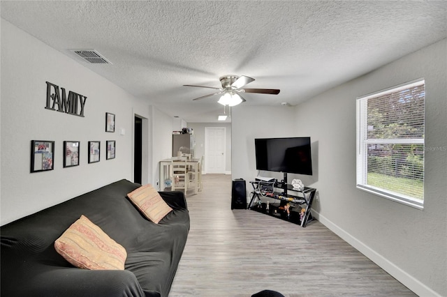 living room featuring ceiling fan, hardwood / wood-style flooring, and a textured ceiling