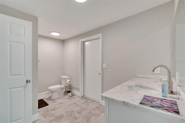 bathroom with toilet, vanity, and baseboards