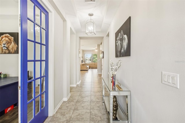 corridor with an inviting chandelier and light tile patterned floors