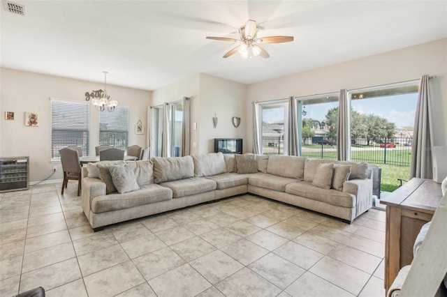 living area with beverage cooler, visible vents, baseboards, light tile patterned flooring, and ceiling fan with notable chandelier