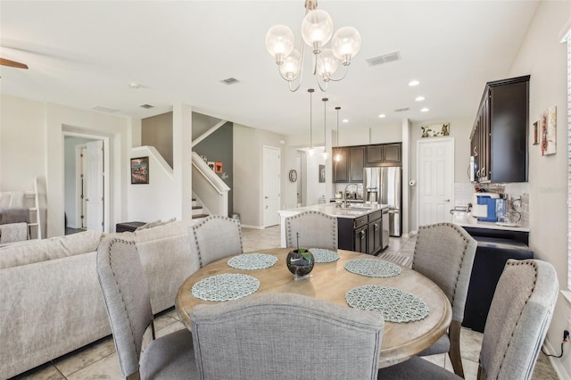 tiled dining space featuring ceiling fan with notable chandelier and sink