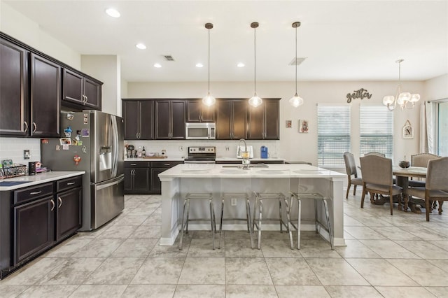 kitchen with visible vents, a breakfast bar, a sink, stainless steel appliances, and light countertops