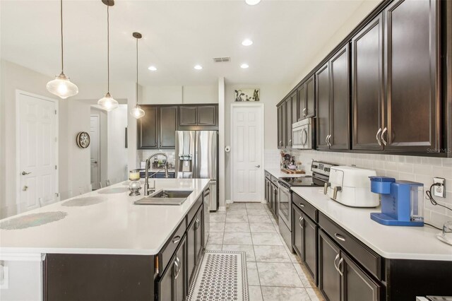 kitchen featuring sink, decorative light fixtures, a kitchen island with sink, appliances with stainless steel finishes, and decorative backsplash