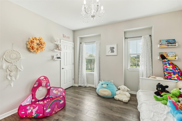 playroom with an inviting chandelier, plenty of natural light, wood finished floors, and baseboards