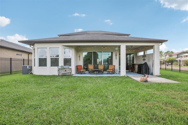 rear view of house with stucco siding, a lawn, and a fenced backyard